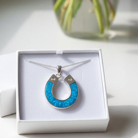 Necklace with a blue pendant in a white box on a light surface with a vase in the background